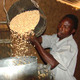 A farmer in Embu, Kenya, loads grain into a metal silo, for more efficient storage