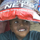 A young Kenyan boy carries a mosquito net A young Kenyan boy carries a mosquito net