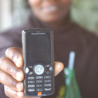 A Kenyan woman holding a mobile phone