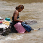 Mujer lavando ropa en un río