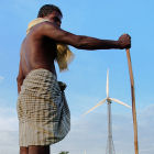A farmer stands in front of a wind farm/India