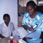 A researcher in Kenya checks a patient's records before giving her a tablet