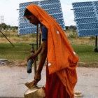 Woman collects water from a solar powered water pump in India