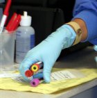 Person wearing medical gloves holding vials.