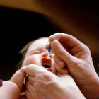Baby, visiting doctor, receiving oral polio vaccine 