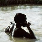 A woman drinks from the river as she bathes, in Senegal