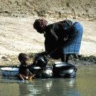 Cleaning cooking utensils in a river, Mali