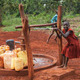 Children collect water from a small local well in their Ugandan village